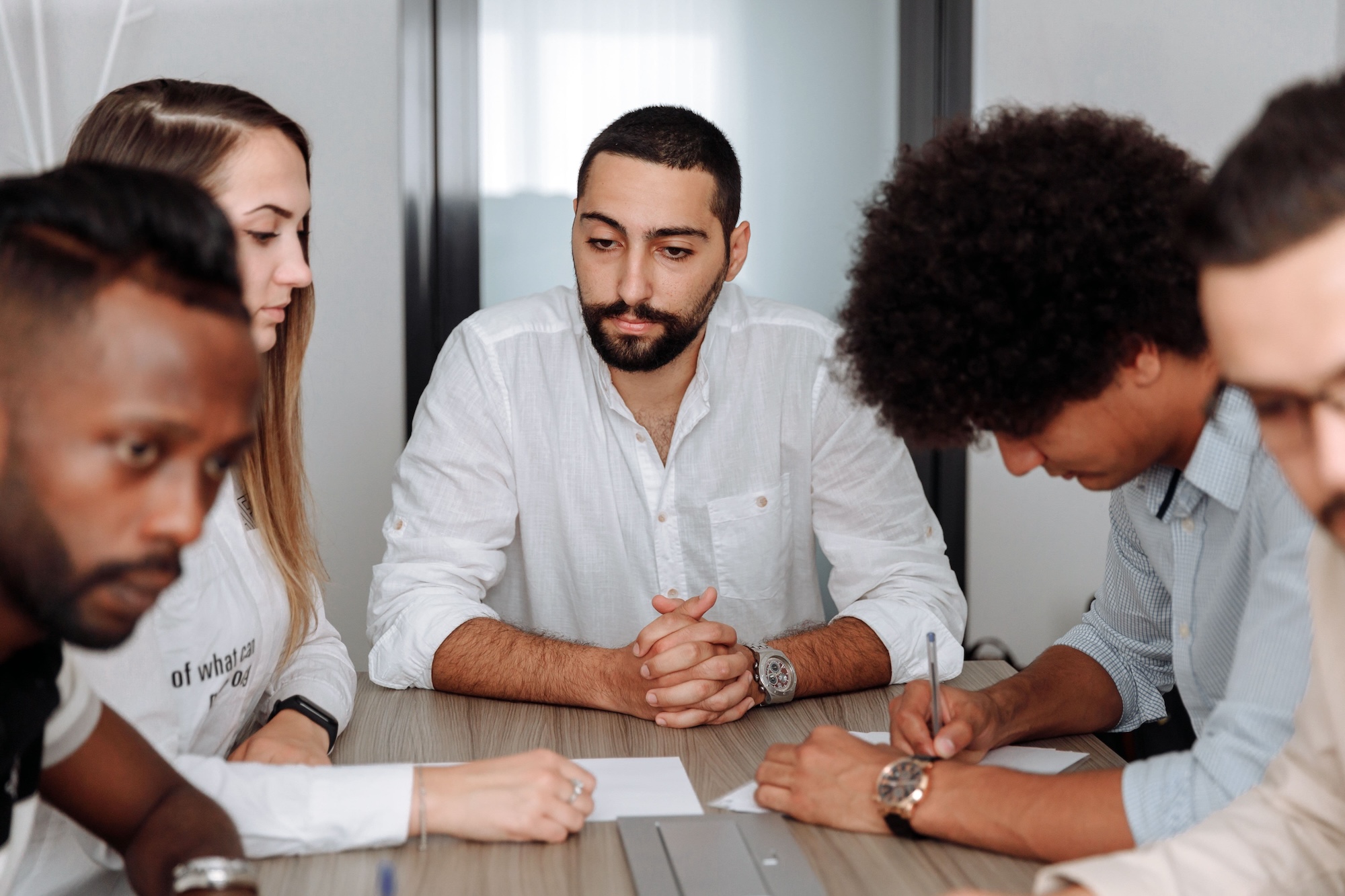A team gathered around a conference table, reviewing and signing documents together.
